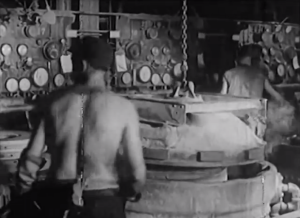 A tire factory worker prepares curing molds for the vulcanizer.