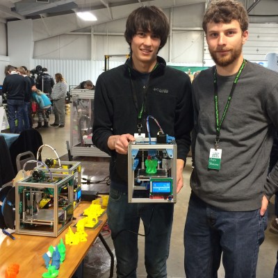 Patrick and Matt hold a running Kitten Printer. The frame is stiff enough that the printer can be held or turned upside down and it can keep printing.