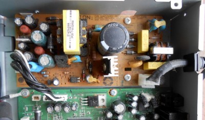 A switch-mode power supply in a set-top box from the mid-2000s. The brown board is the power supply, and all the components on it to the right of the yellow transformer are live.