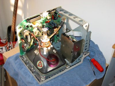 The interior of a Mac Plus, showing the red EHT lead and insulating cup on the side of the CRT. Blake Patterson, [CC BY 2.0 ], via Wikimedia Commons