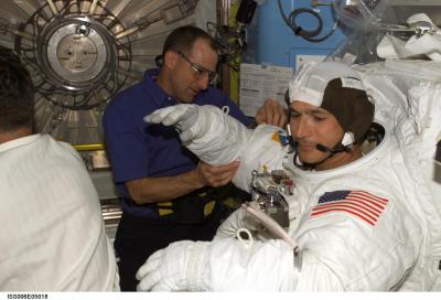 Flight engineer Petit helping MS Herrington don his EMU space suit, Source: NASA