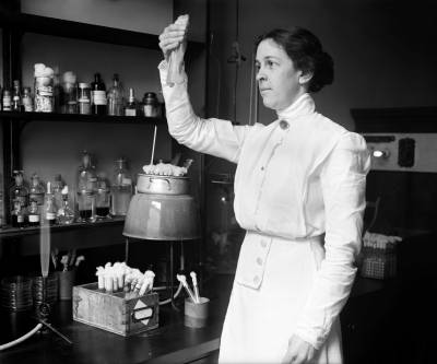 Portrait of Alice Evans in a laboratory, observing a test tube