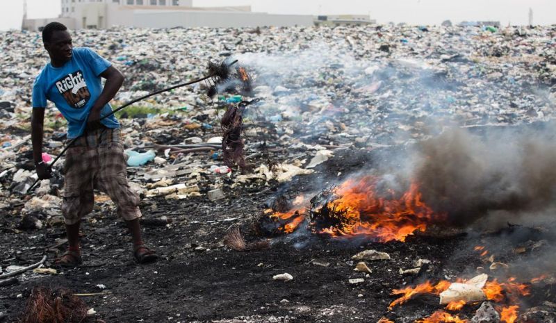 A man standing over burning electronics