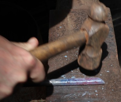 I've squared off the end of my piece of round stock. The bright sunlight makes it difficult to see, but the metal is now a dull red and needs to go back in the fire.