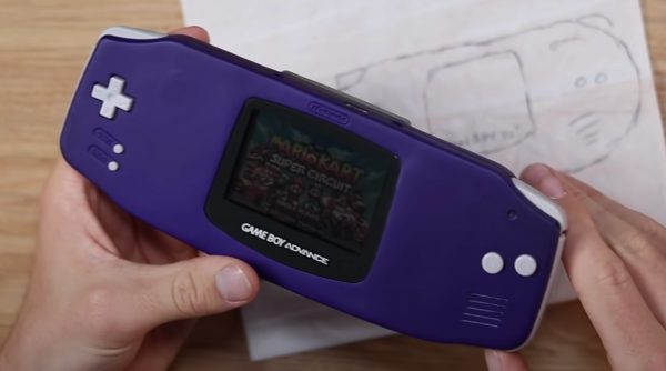 two hands holding a wider version of a purple gameboy advance