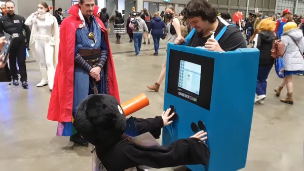 A conventiongoer plays Pokemon on a working Color Game Boy costume.