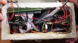 View of the inside of the clock's concrete enclosure, showing a messy array of wires and modules, held together with lots of hot glue and electrical tape.