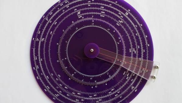 front view of a purple acrylic slide rule with white ink scale markings.