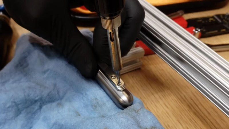 A soldering iron applied to a stuck threadlocked screw in a titanium pen