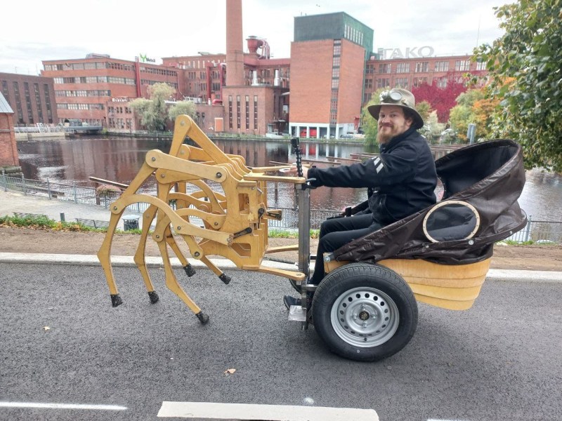 A man riding a buggy pulled by a wooden contraption