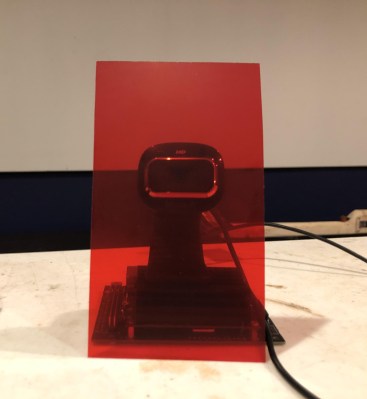 A webcam on top of a Jetson Nano, with a red color filter in front