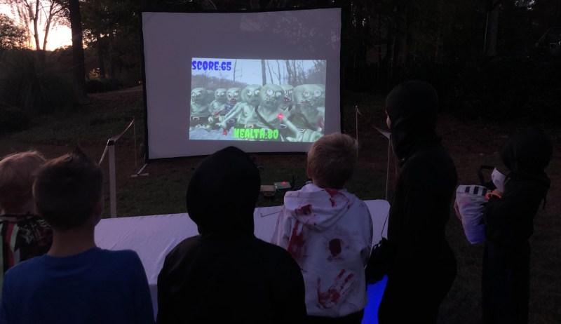 Children playing a zombie shooting game on a big screen