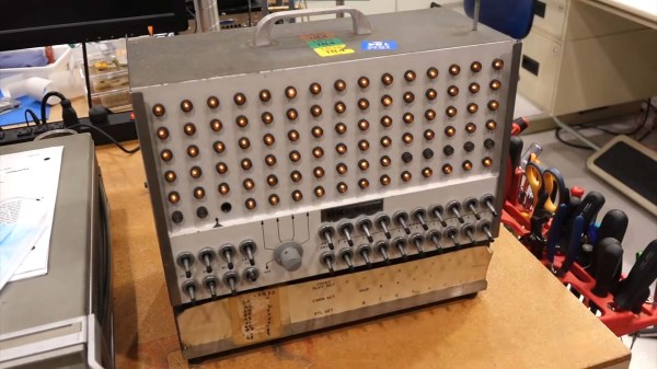 A briefcase sized electronic machine with many indicator lamps and switches