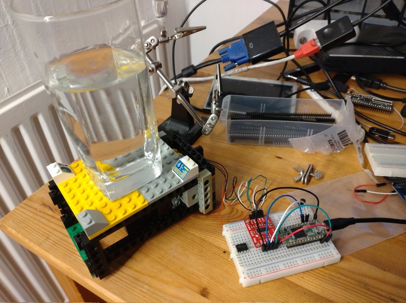 A Lego cup holder with a glass of water and electronics on a breadboard