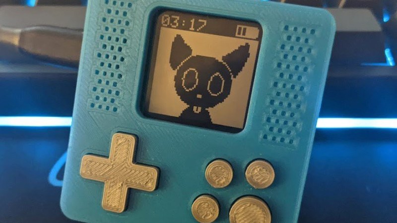 The PawPet board in a 3D-printed case, with a d-pad on the right and four buttons on the left. On its small monochrome screen, there's a cat-like pet looking at you.