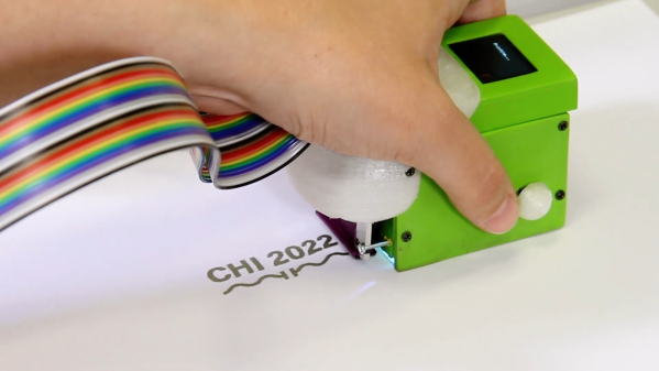A handheld printer printing "CHI 2022 and a capacitor symbol