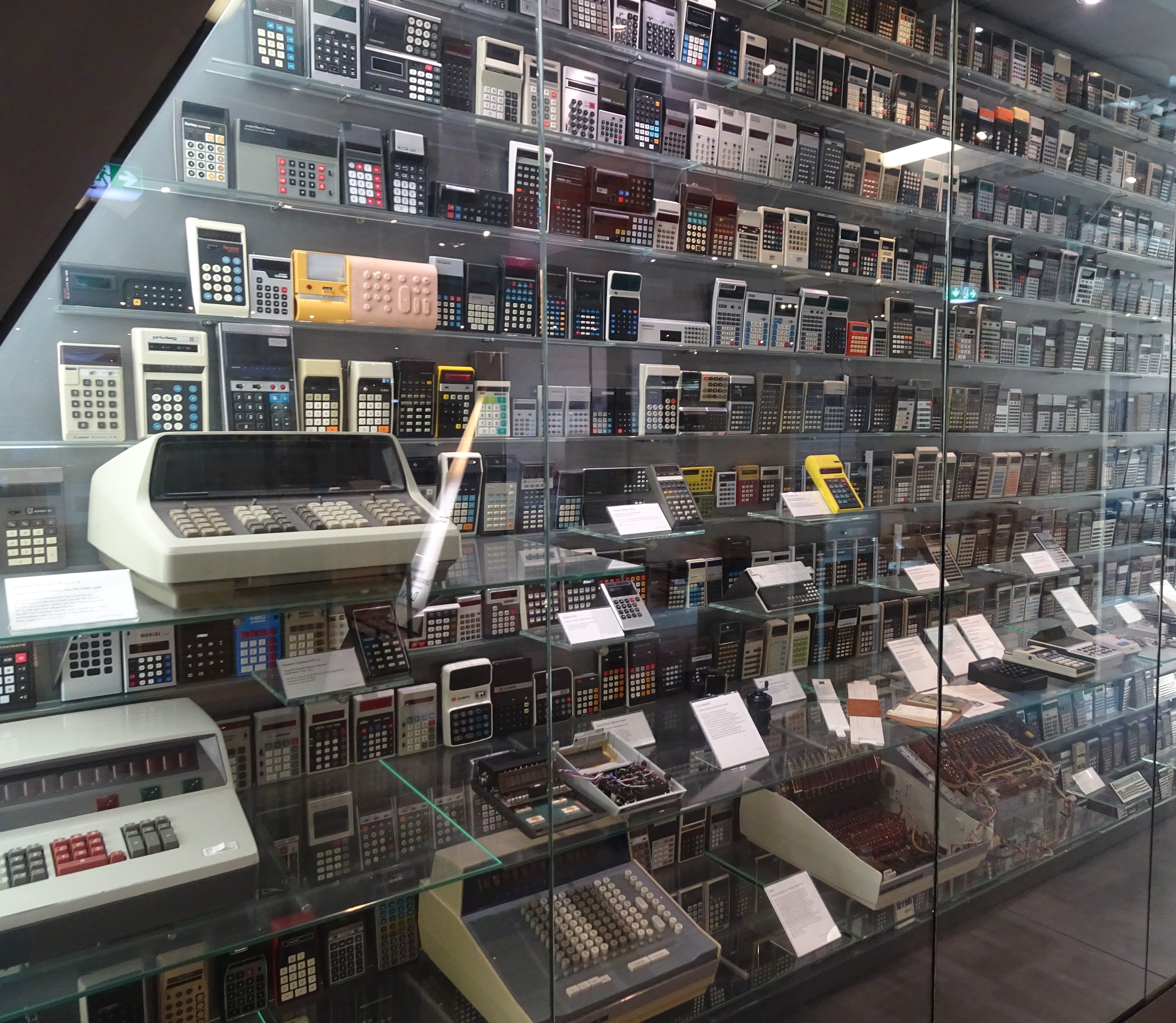 A glass display case with hundreds of electronic calculators inside