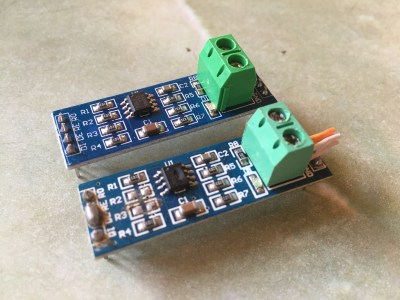 Two "MAX485" modules side by side. The top ine is brand new, while the last one has some resistors removed, a piece of twisted pair inside the terminal block, oh, and an IC with a crater