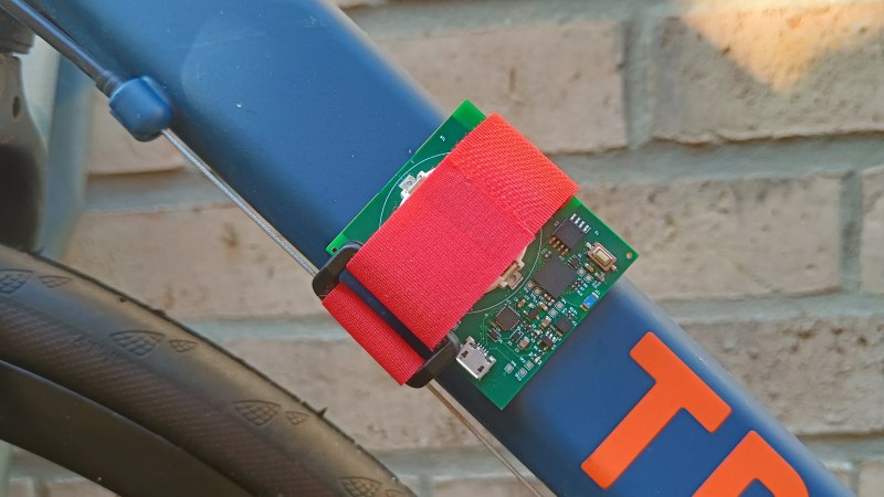 The Tracer board strapped to the frame of a bicycle with a red Velcro strap