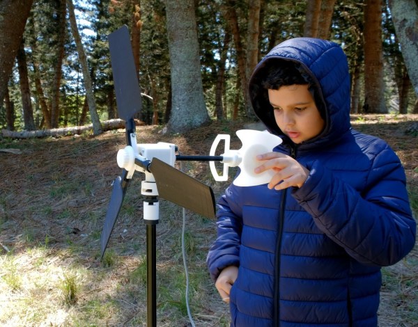 A boy looking at a small wind turbine