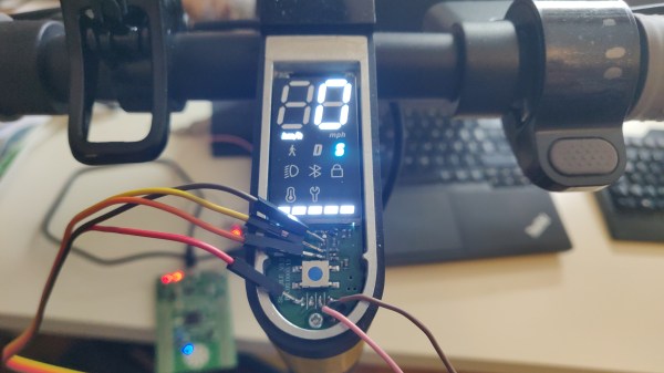 The dash of Xiaomi Mi 1S scooter, with the top panel taken off and an USB-UART adapter connected to the dashboard, sniffing the firmware update process