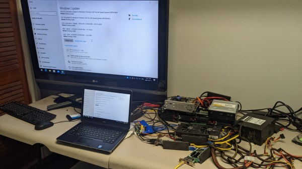 Picture of the setup described in the article, with PCI-E cards strewn around the desk, all interconnected, and a powered-up laptop, a large TV screen behind the laptop