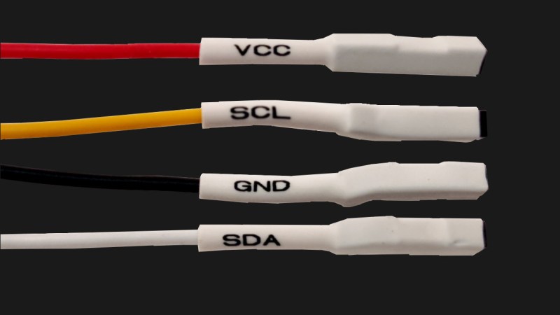 Four jumper wires with white heatshrink on them, labelled VCC, SCL, SDA and GND