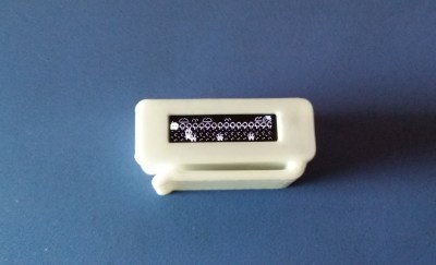 A small plastic case with an OLED screen showing a side-scrolling game