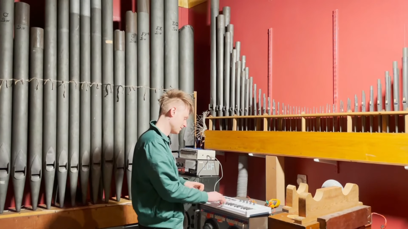 A man playing a pipe organ through a MIDI keyboard