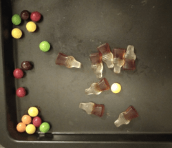 gummy colas and skittles in a baking sheet