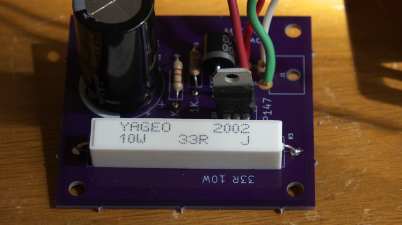 The circuit, assembled on a purple PCB, with a large capacitor and a sizeable white resistor, wires soldered to holes in the PCB
