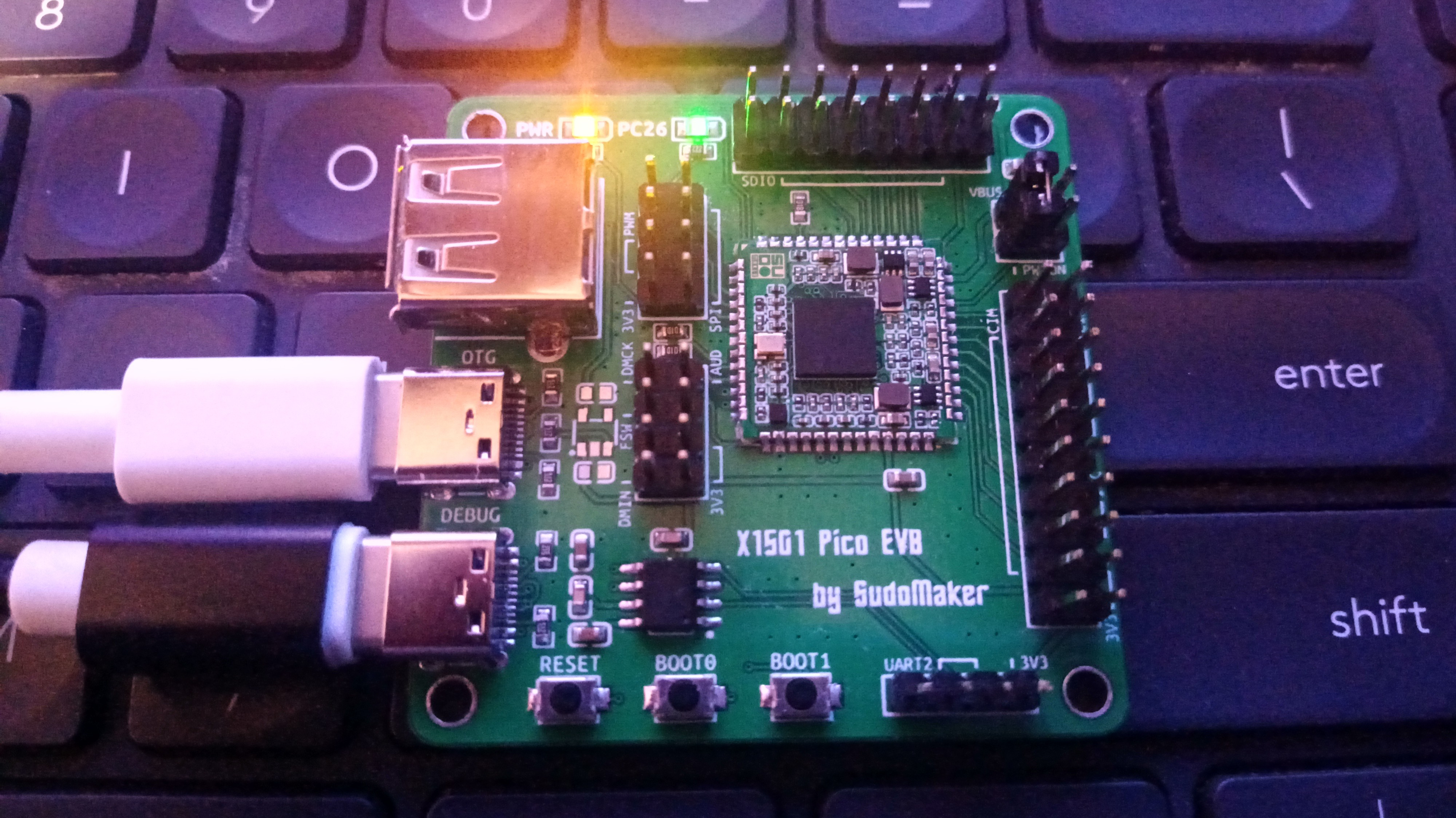 The SoM on an evaluation board, with two LEDs shining, one USB-C cable connected for power and another plugged into the OTG port