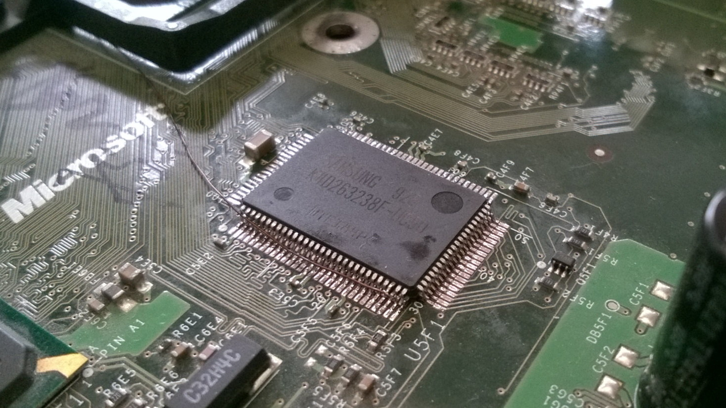 Picture of the modification as it's being performed, with an extra chip stacked on top of the original, extra magnet wire connection going to the chip select line pin