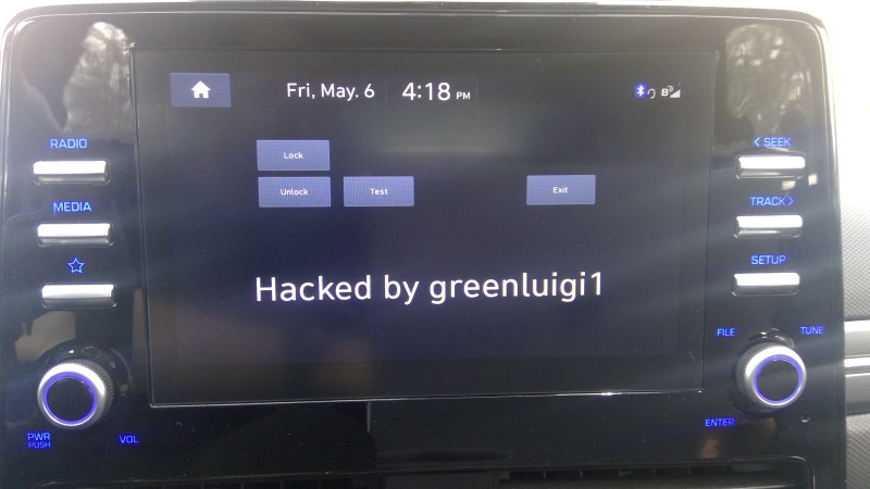 Photo of the head unit , with "Hacked by greenluigi1" in the center of the UI