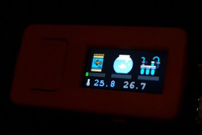 A small IoT device with an LCD screen showing aquarium-related information