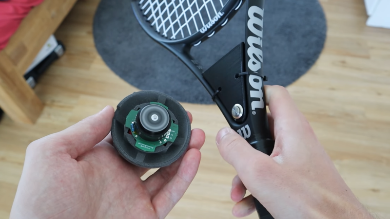A tennis racket and a tennis ball with a spinning motor inside