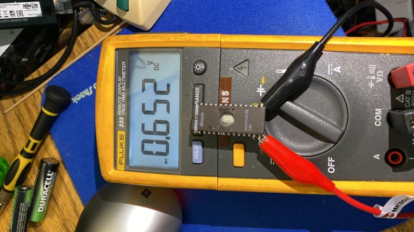 A multimeter connected to the EEPROM chip with crocodile clips, showing that there's a 0.652V diode drop between GND and one of the IO pins