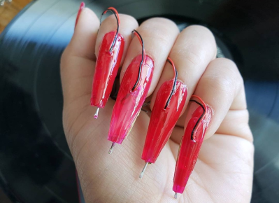 Photograph of hand with record needs through glue-on nails