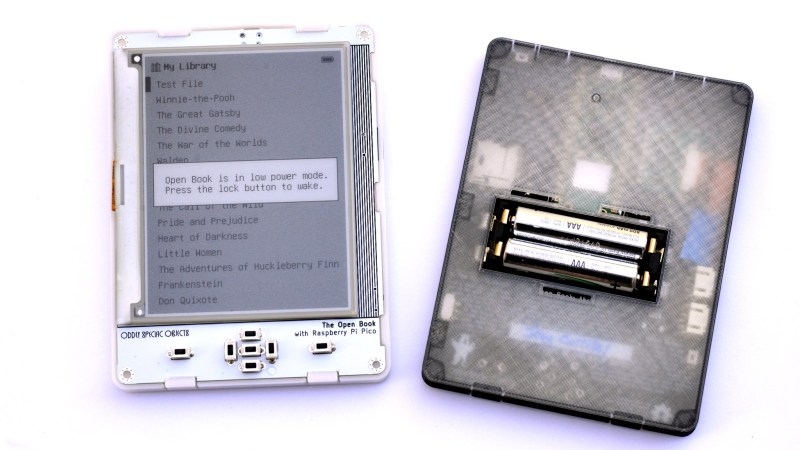 Two e-readers side to side. On the left, you can see the frontal view, showing text on the e-ink screen. On the right, you can see the backside with a semi-transparent 3D-printed cover over it, and two AAA batteries inside a holder in the center.