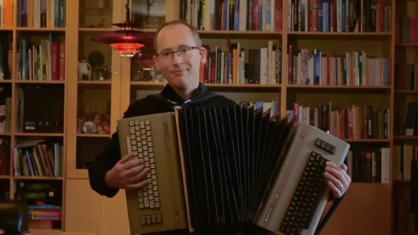 A man playing an accordion-like instrument made from two Commodore 64s