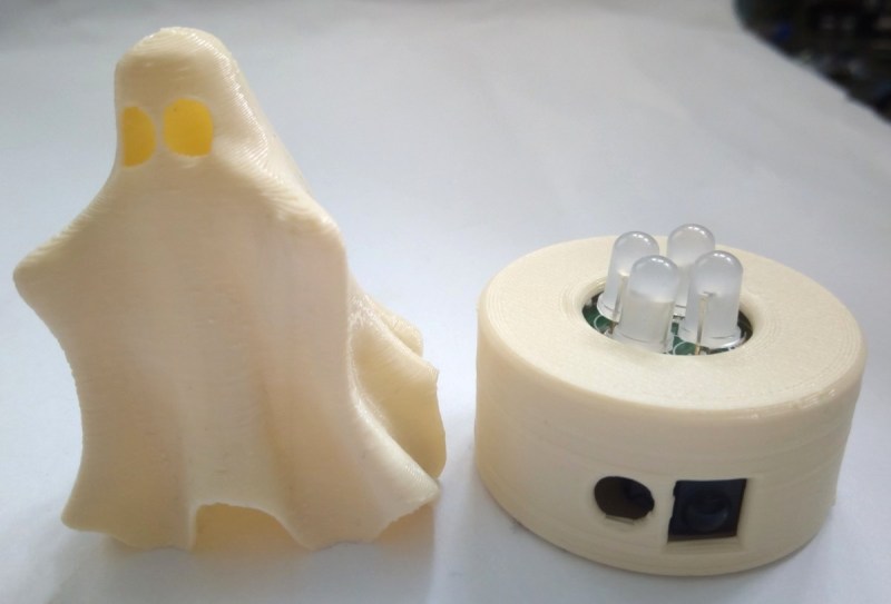 A 3d printed ghost next to the base of an LED tea light that has 4 LEDs poking out and the IR receiver port and micro-USB connector showing.