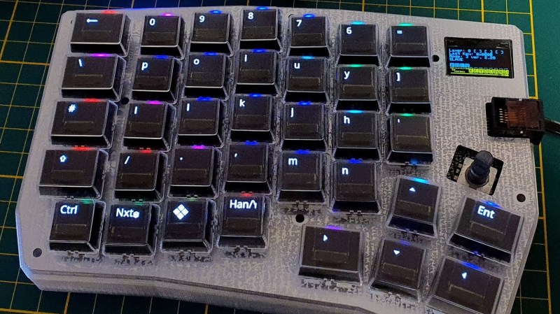 A left-hand side unit of a split keyboard. The keys are black with RGB lighting and the key legends are displayed on small OLED screens in each key.