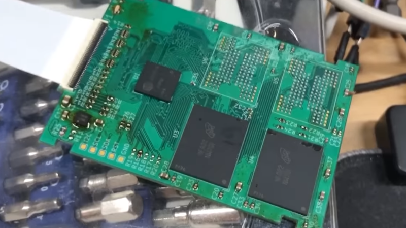 The SSD described, a green board with a ZIP connector, a controller chip and two out of four NAND chips populated. There's traces of flux on the chip, as it hasn't been washed after soldering yet.