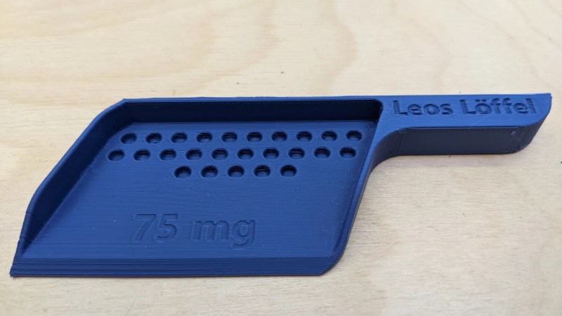 The dosing spoon shown, with many round openings for medication pellets to go into