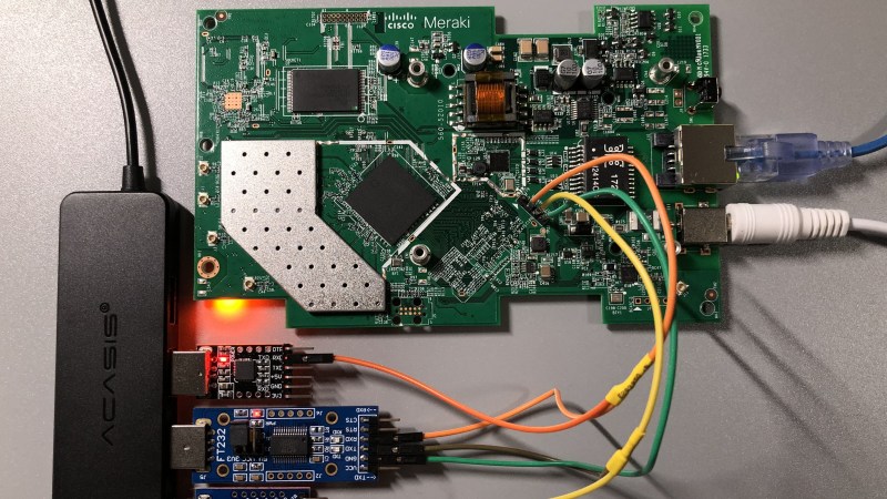 The Meraki AP PCB on a desk, case-less, with three USB-UARTs connected to its pins - one for interacting with the device, and two for monitoring both of the UART data lines.