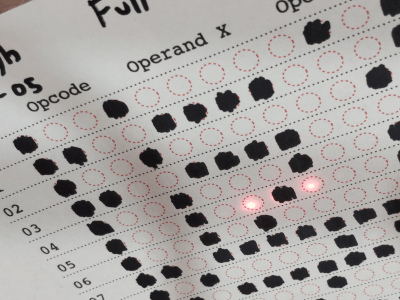 Printed paper faux punch card showing read LEDs and an array of set and reset bits of the encoding