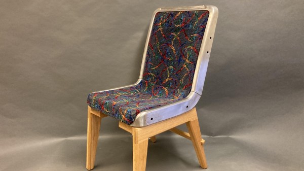 A multi-colored chair with a stainless steel frame sits on wooden legs against a grey background.