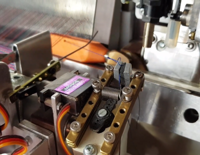 A detail of an automatic loom, showing the end of the weft being clamped as the shuttle starts its run