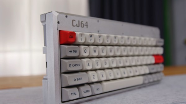 A grey keyboard with orange and dark grey accents is angled away from the camera. The keys nearby are clearly distinguishable in the foreground but blurry toward the back/right. The keyboard is quite thick as it also contains a computer motherboard.