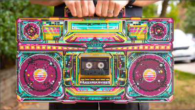 The front of a PCB boombox being held at the top, with a cassette tape in the middle